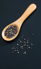 Chia seed in wooden spoon on black chalkboard