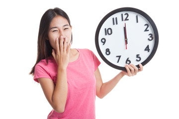 Sleepy young Asian woman with a clock in the morning.