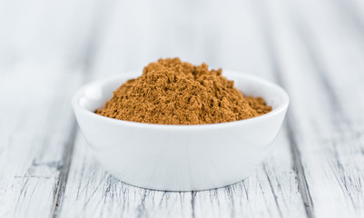 Portion of Cinnamon Powder on wooden background (selective focus