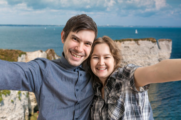 Young happy couple is taking selfie photo on vacation near sea.