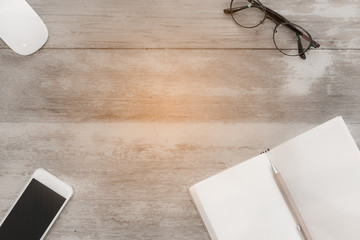 Top view work space notebook,glass,mobile phone  and brown penci