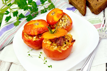 Tomatoes stuffed with bulgur and meat in plate on board