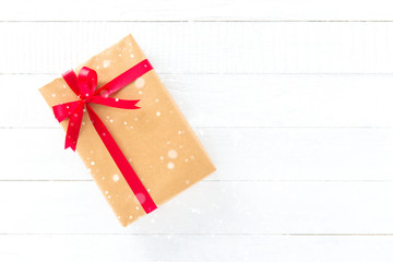Gift box with red ribbon on white wood background
