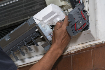 Repairman fixing and cleaning air conditioner unit

