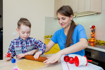 Happy mother and son whisking dough in christmas decorated kitch