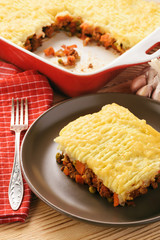 Shepherd pie (portion) on plate on wooden table.