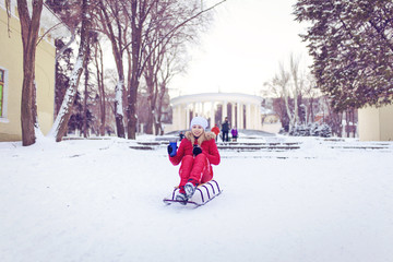 Smiling girl on a sledge in the snow in winter