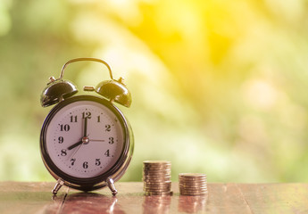 Alarm clock and rows of coins with natural background, Money and saving concept