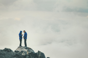 Couple Travelers in love standing on cliff together enjoying cloudy foggy mountains landscape Travel Lifestyle freedom concept adventure vacations outdoor