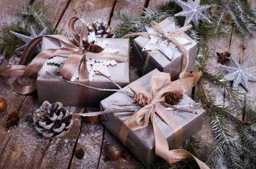 Gift boxes on old wooden background with silver stars, cones, hazelnut, anise, tape, ribbon, snowflakes.