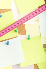 Folding rule on notice board with empty reminder notes. Concept image of measurement, construction...