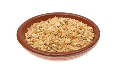 Dried minced garlic in a small bowl isolated on a white background.