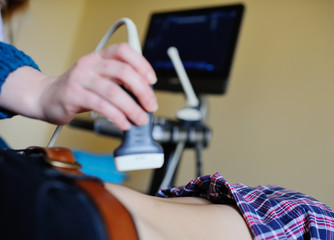 Doctor makes the patient women abdominal ultrasound. Pregnancy. Ultrasound Scanner in the hands of a doctor. Diagnostics. Sonography.