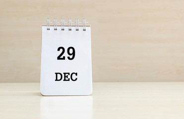 Closeup surface note book with black 29 dec word in page on blurred brown wood desk and wood wall textured background with copy space under window light