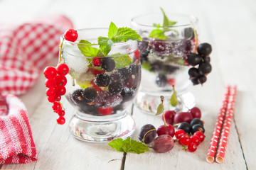 summer drink with berries and ice in a glass on a table, selective focus
