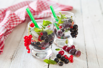 summer drink with berries and ice in a glass on a table, selective focus