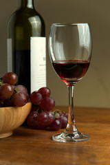 Wine bottles with glass and grape on wooden table background