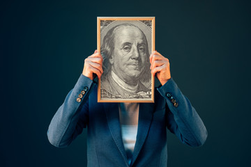 Businesswoman holding Benjamin Franklin 100 USA dollar portrait - obrazy, fototapety, plakaty
