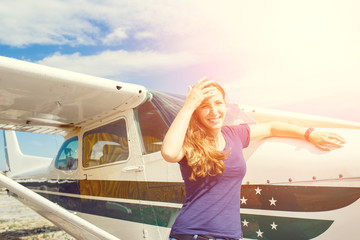 Young happy woman standing near private plane before flight