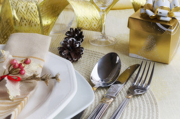 Beautiful decoration for festive dinner. Christmas table settings in gold tone: cutlery with  napkin on linen tablecloth. Winter holiday background. Merry Christmas or Happy New Year concept.