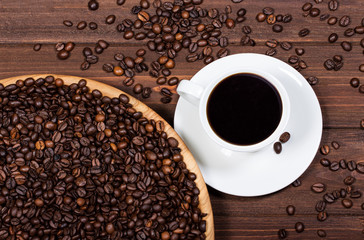 cup of coffee and coffee beans on a wooden table. Horizontal top view