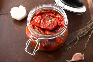 Sun dried tomatoes with herbs and sea salt in olive oil in a gla