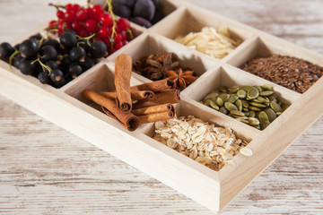mix of ingredients for a breakfast - oats, a seed, cinnamon and berries on a tray, selective focus
