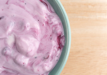Bowl of blueberry gourmet yogurt on a wood table top close view.