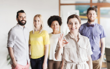 Obraz premium happy woman showing ok over creative office team