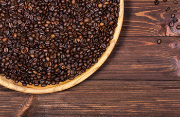 large wooden platter with coffee beans on the table. Horizontal top view. Empty space to place text