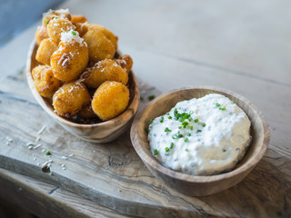 Potato gnocchi, small dough dumplings in breadcrumbs served in a wooden rustic bowl with a dip.