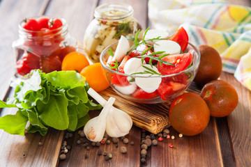 ingredients for salad - cheese, tomatoes, greens and garlic on a table, selective focus