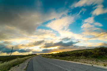 Picturesque landscape scene and sunset above road