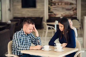 Young couple arguing in a cafe. She's had enough, boyfriend is apologizing. Relationship problems.