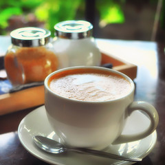 Cup of coffee on wooden table and window view background