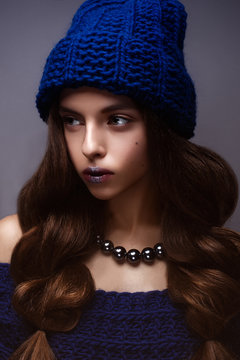 Beautiful girl in winter knitted hat blue color with a necklace around the  neck of pearls. Young model with gentle makeup and silver lips. Warm winter  picture. Beauty face. Stock Photo |