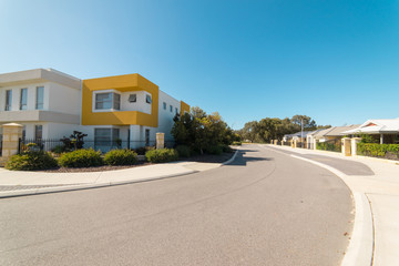 Fototapeta na wymiar Asphalt road with modern terrace house in front on blue sky background. Yanchep Beach Town , Perth , Western Australia .
