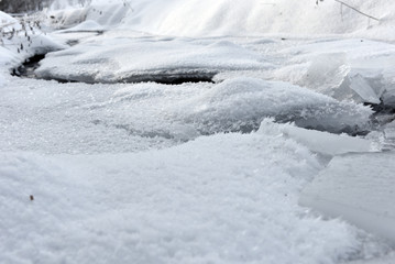 Fototapeta na wymiar Frozen ice crystals among a small river