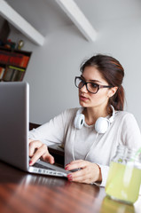 Young female student  at home.She sitting in her living room and typing something on laptop.E-learning.