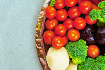 Vegetables on a plate. Broccoli, peeled raw potatoes, peeled boiled beets, red peppers, cherry tomatoes