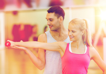 male trainer with woman working out with dumbbell