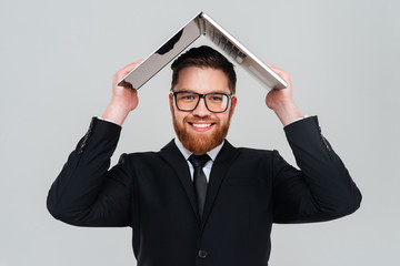 Smiling business man holding laptop overhead