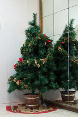Christmas tree in the corner near the mirror