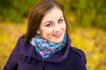 Portrait of a smiling beautiful girl on the blurry background of autumn leaves