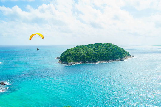 Skydiver flying over the water with island. Paragliding concept.