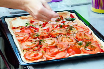 Woman hands grating cheese on the pizza. Young woman preparing the pizza in the kitchen.