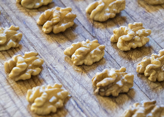 Shelled walnuts in a row on rustic wood table. Natural light.