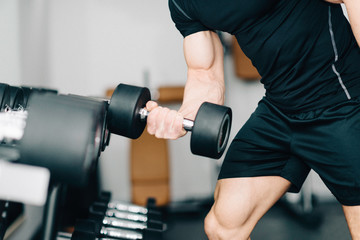 Fototapeta na wymiar Dumbbell biceps. Man exercise in the gym