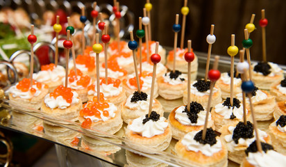 Tasteful snacks with caviar stand on glass tray