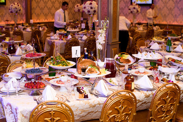 Golden chairs stand at rich served dinner tables